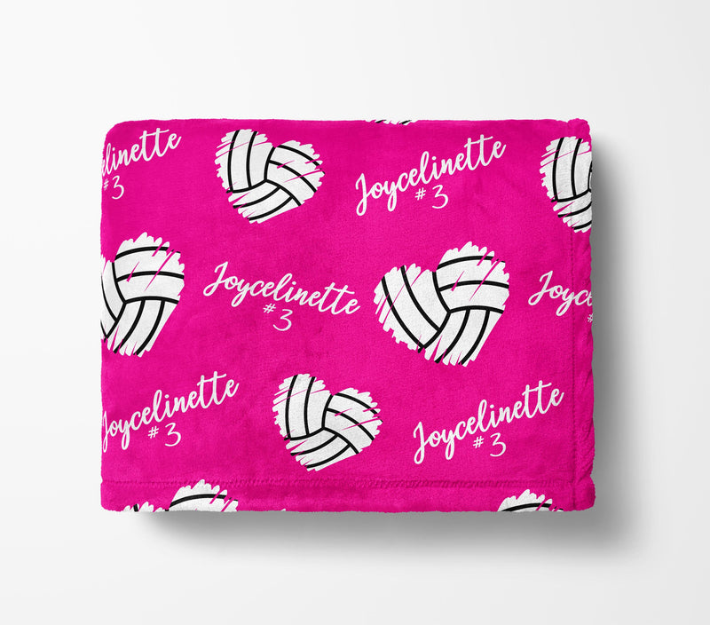 The image is a pink blanket with a repeating pattern of volleyball hearts and the name "Joycelinette" written on it.