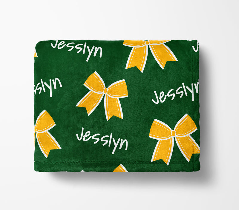 a green blanket with yellow bows and the name "Jesslyn" printed on it.