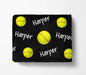 A black blanket with yellow softball images and the name "Harper" written on it in white text.