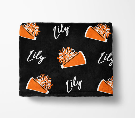 a black blanket with a repeating pattern of orange cheerleading pom-poms and the name "Lily" written in white.