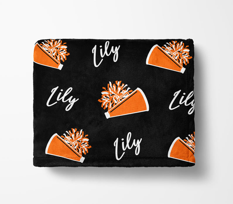 a black blanket with a repeating pattern of orange cheerleading pom-poms and the name "Lily" written in white.
