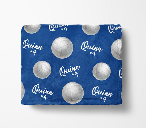 a blue blanket with a repeating pattern of volleyball images and the name "Quinn #4" printed on it.