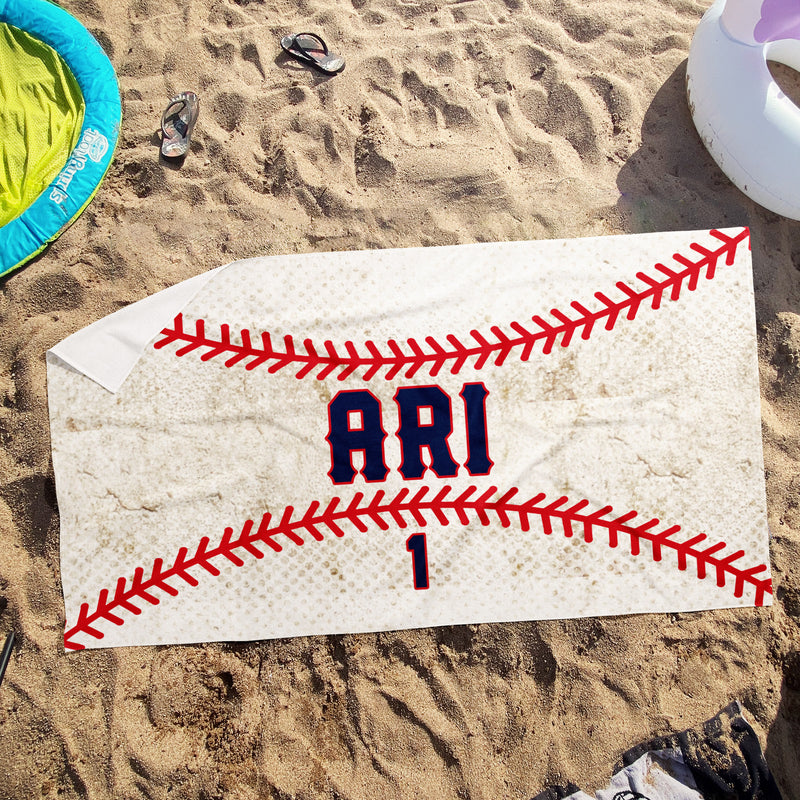 a towel with a baseball on it laying in the sand