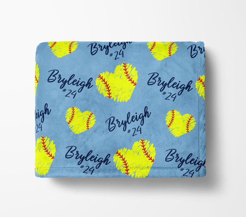A blue blanket with yellow softball-shaped hearts and the name "Bryleigh" printed on it.