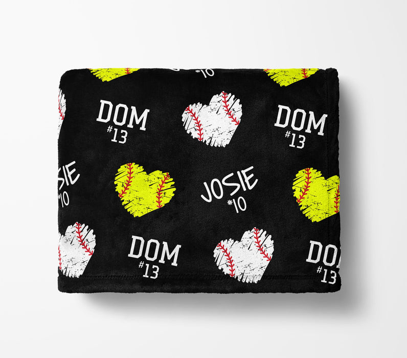 a black blanket with a repeating pattern of baseballs and hearts in yellow and white colors.