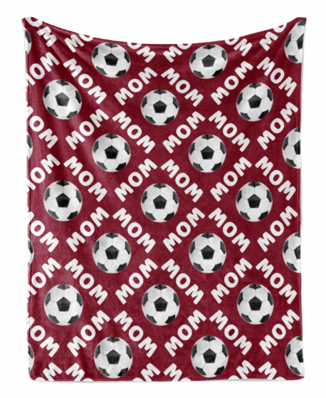 a red blanket with a repeating pattern of soccer balls and the word "MOM" printed on it.