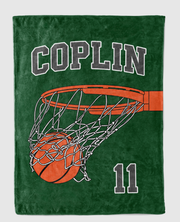 A green blanket with a basketball net and a basketball printed on it.
