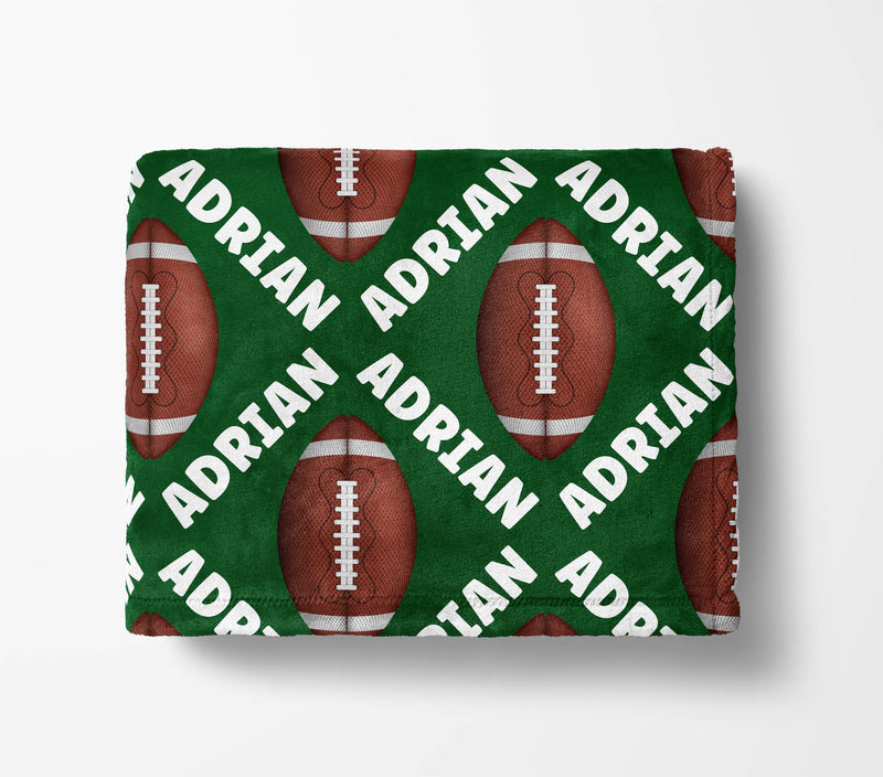 a green blanket with a repeating pattern of red footballs and the name "ADRIAN" written in white.