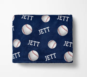 a navy blue blanket with a repeating pattern of baseballs and the word "Jett" printed on it.