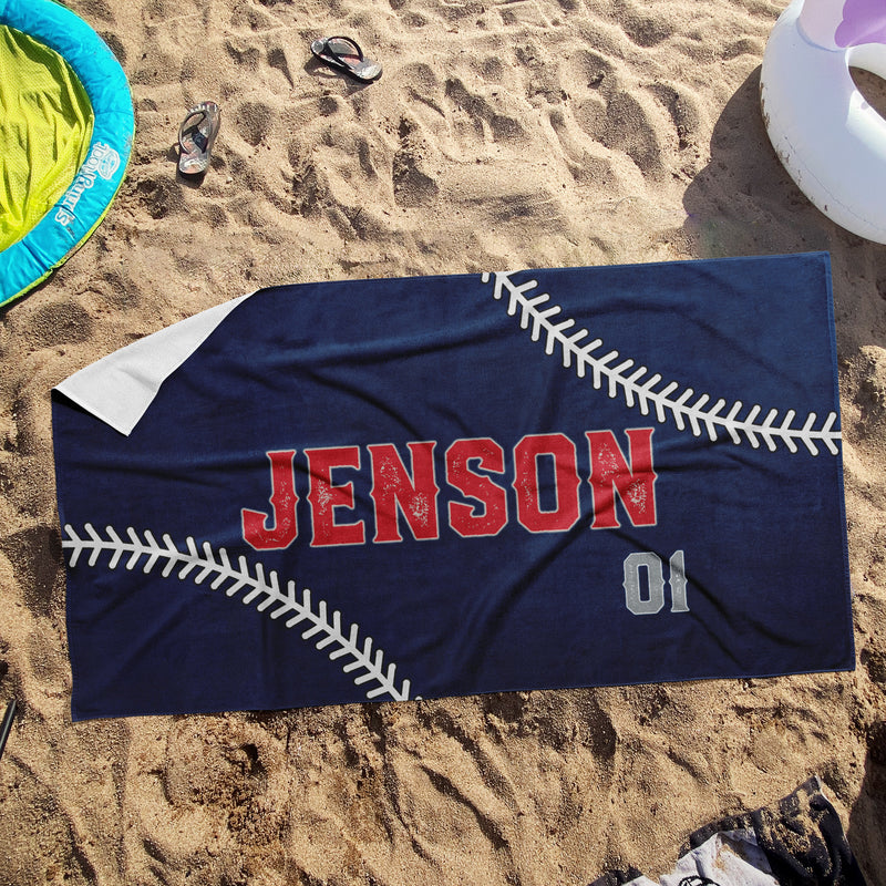 a towel with a baseball on it laying in the sand