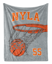 A gray blanket with an illustration of a basketball hoop and a basketball in the net.