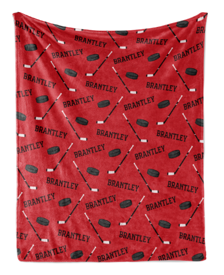 a red blanket with a repeating pattern of hockey sticks and puck silhouettes.