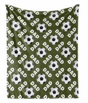 a repeating pattern of soccer balls and the word "DAD" on a green fabric background.