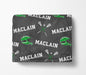 a gray blanket with a repeating pattern of green lacrosse equipment and the word "MACLAIN" printed on it.