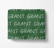 The image is a green blanket with the word "GRANT" repeated multiple times in white text.